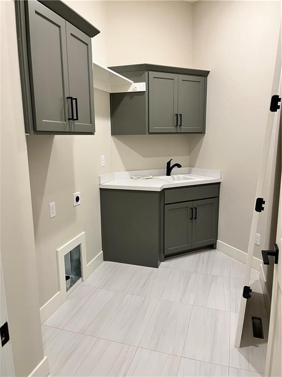 washroom with a sink, baseboards, cabinet space, and hookup for an electric dryer