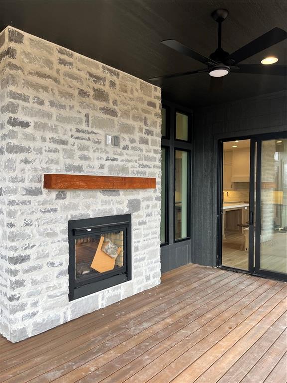 wooden deck featuring a stone fireplace and ceiling fan