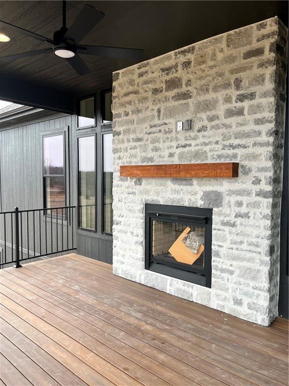 deck with a stone fireplace and ceiling fan