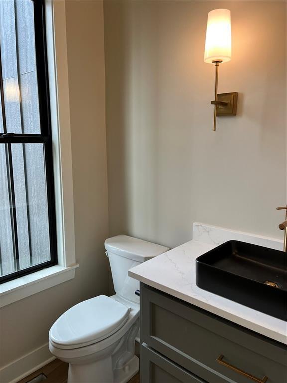 half bath with vanity, toilet, and baseboards