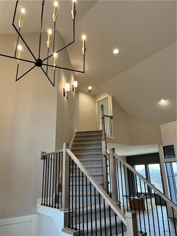 staircase featuring a chandelier, recessed lighting, and high vaulted ceiling