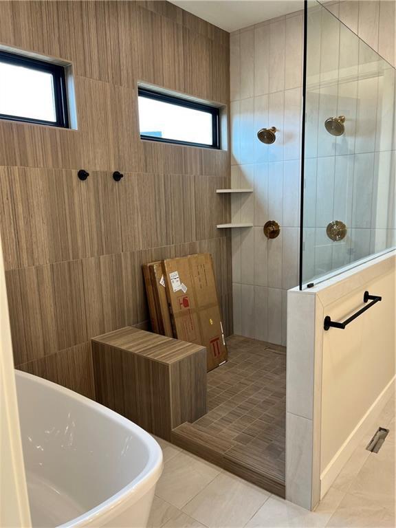 full bathroom with tile patterned floors, a wealth of natural light, walk in shower, and a freestanding tub