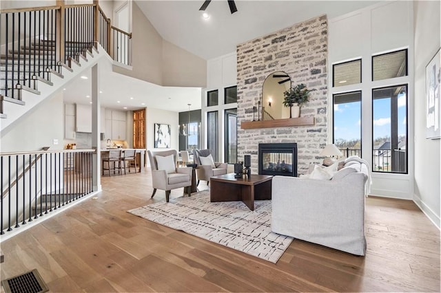 living area featuring a towering ceiling, a stone fireplace, and wood finished floors