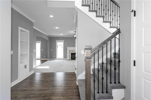 entryway with arched walkways, recessed lighting, dark wood-type flooring, a fireplace, and ornamental molding