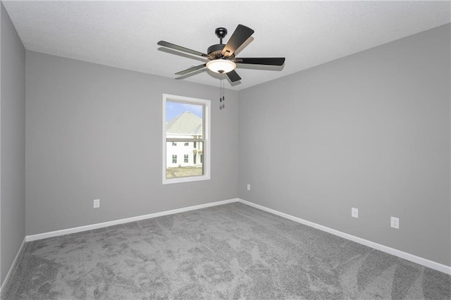 spare room featuring carpet floors, a textured ceiling, baseboards, and a ceiling fan