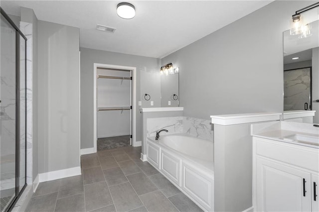 full bath with a stall shower, visible vents, a walk in closet, vanity, and a bath