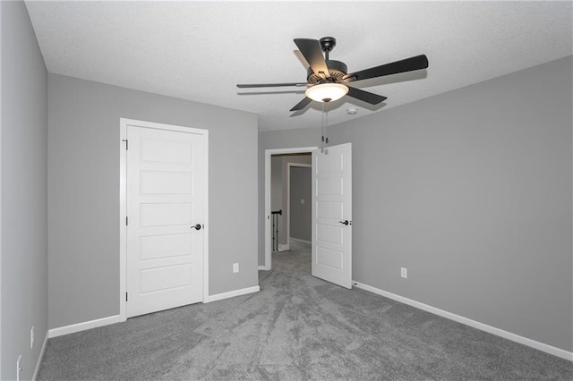 unfurnished bedroom with a textured ceiling, carpet flooring, a ceiling fan, and baseboards