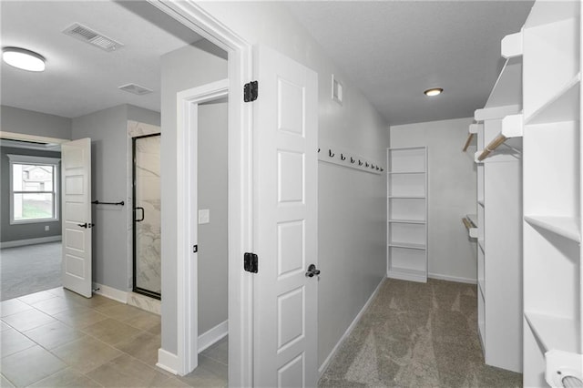 spacious closet with tile patterned flooring, visible vents, and carpet flooring