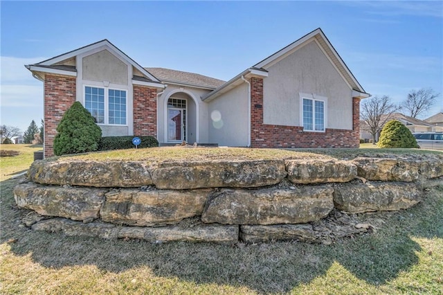 ranch-style house featuring stucco siding and brick siding