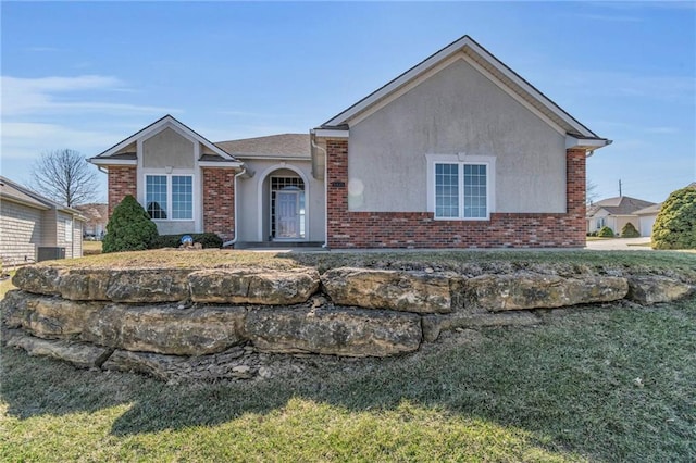 single story home with brick siding, stucco siding, and a front lawn