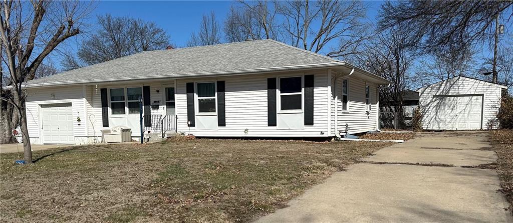 2002 Quail St, Harrisonville, MO 64701 - ranch-style house with driveway, a porch, an attached garage, an outdoor structure, and roof with shingles