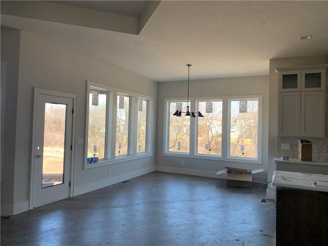 unfurnished dining area with wood finished floors, baseboards, and a textured ceiling