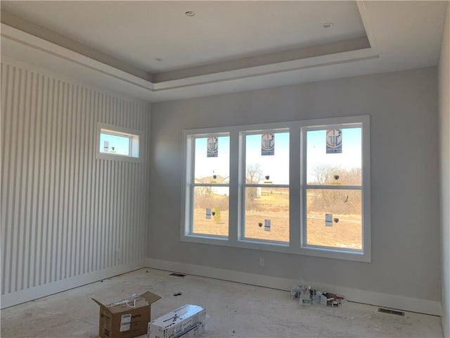 unfurnished room with a tray ceiling and baseboards