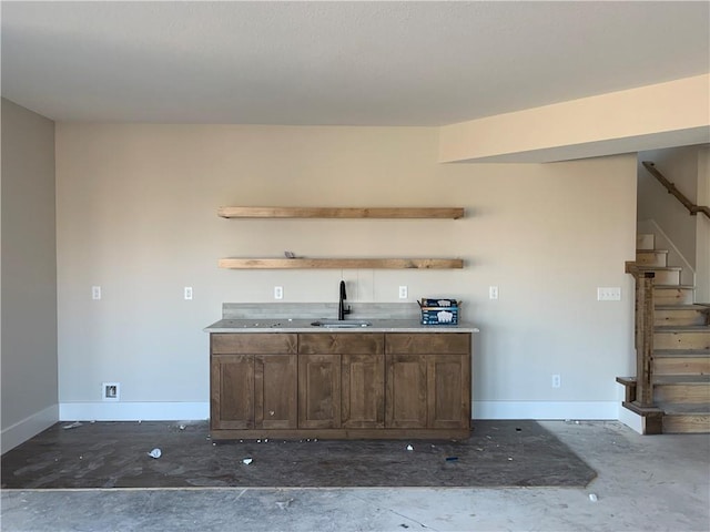 bar featuring stairway, baseboards, and a sink