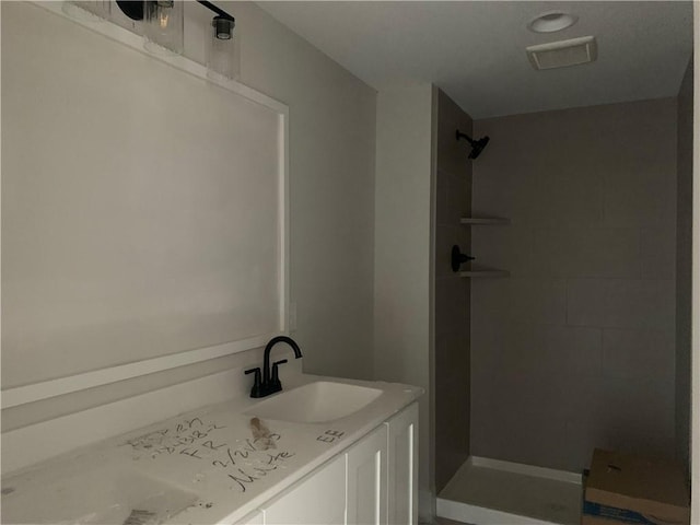 full bath featuring a tile shower and a sink