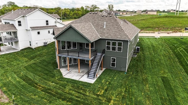 1510 NW 106th Ter, Kansas City, MO 64155 - rear view of house featuring stairway, a patio, roof with shingles, and a lawn