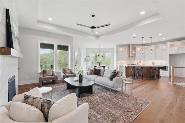 1510 NW 106th Ter, Kansas City, MO 64155 - living room featuring recessed lighting, light wood-style flooring, a raised ceiling, and ceiling fan with notable chandelier