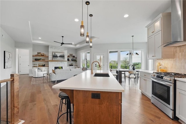 1510 NW 106th Ter, Kansas City, MO 64155 - kitchen featuring ceiling fan, stainless steel gas stove, a sink, a raised ceiling, and wall chimney exhaust hood