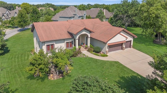 view of front facade with stucco siding, a front lawn, driveway, a garage, and a tiled roof