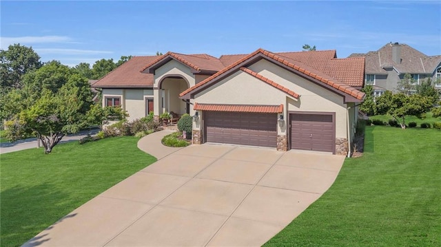 mediterranean / spanish-style home with stucco siding, stone siding, an attached garage, and a front yard