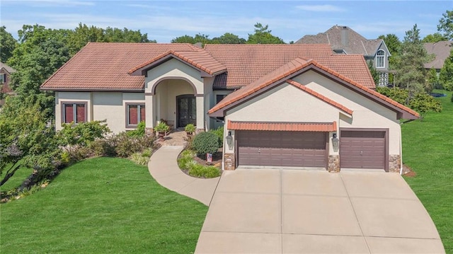 mediterranean / spanish house with a garage, stone siding, a front yard, and stucco siding