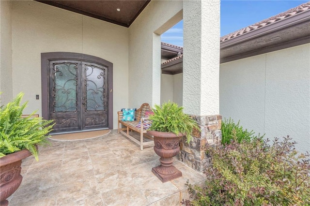 entrance to property featuring stucco siding, french doors, and a tile roof