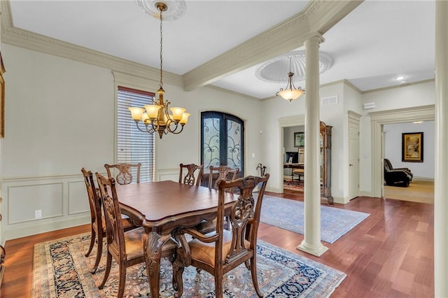 dining room featuring decorative columns, wood finished floors, and ornamental molding