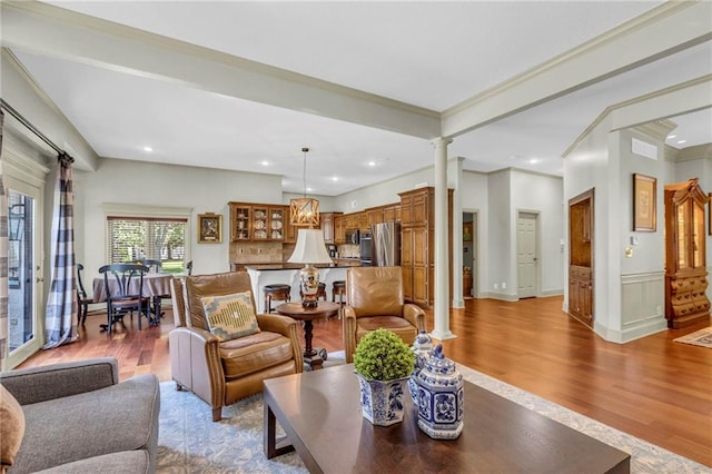 living area featuring recessed lighting, ornamental molding, ornate columns, and wood finished floors