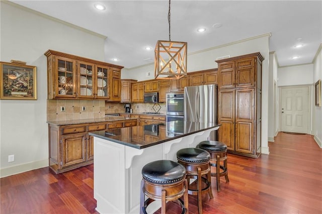 kitchen with dark wood-type flooring, ornamental molding, brown cabinets, and stainless steel appliances