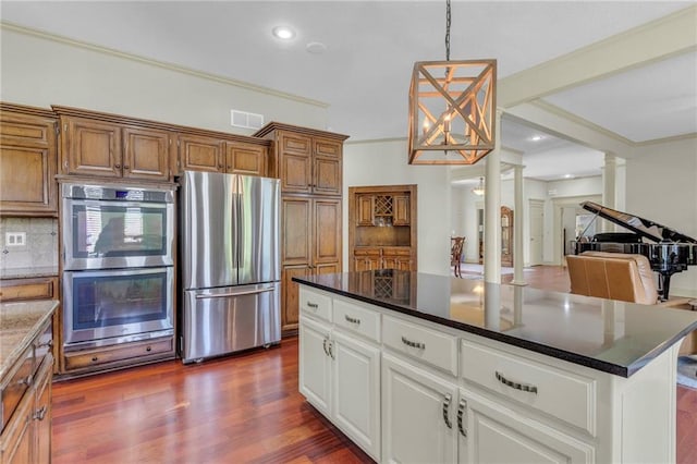 kitchen featuring tasteful backsplash, visible vents, dark wood-type flooring, appliances with stainless steel finishes, and ornate columns