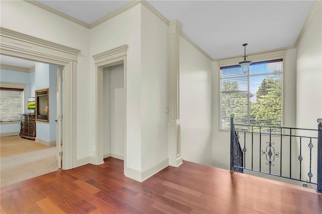 unfurnished room with a wealth of natural light, wood finished floors, and ornamental molding