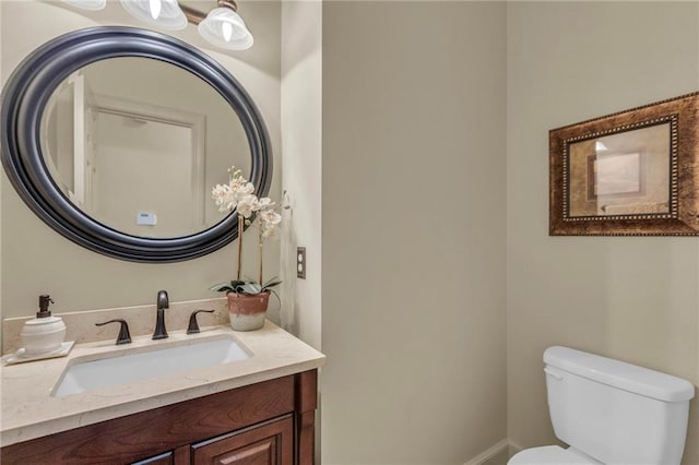 bathroom featuring vanity, toilet, and baseboards