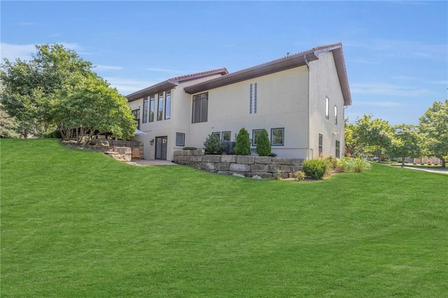 rear view of property with stucco siding and a lawn