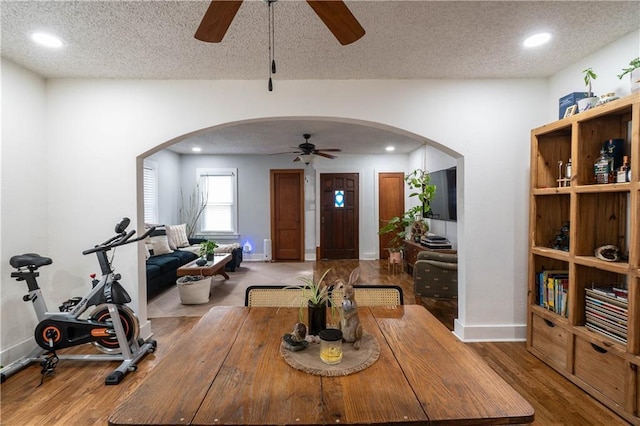 interior space with arched walkways, a textured ceiling, and wood finished floors