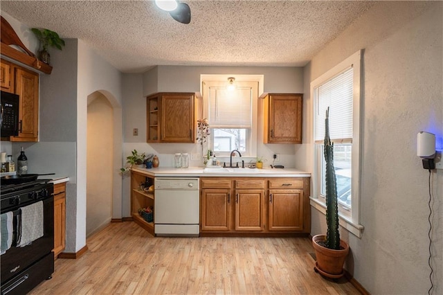 kitchen with brown cabinets, light wood-style flooring, and black appliances