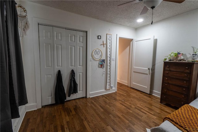 bedroom with a textured ceiling, ceiling fan, dark wood-type flooring, baseboards, and a closet