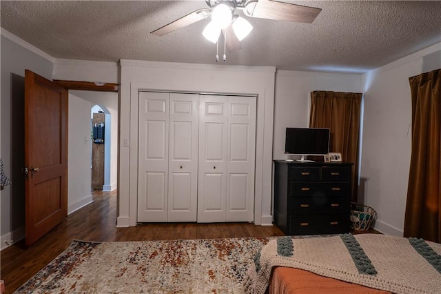 bedroom featuring arched walkways, a closet, dark wood finished floors, and a textured ceiling