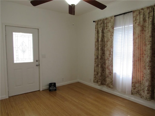 foyer entrance with a wealth of natural light, a ceiling fan, baseboards, and wood finished floors