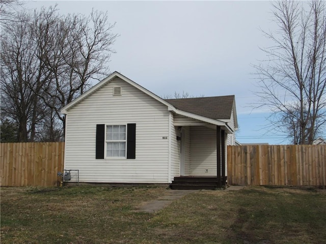 view of front of house with a shingled roof, a front yard, and fence