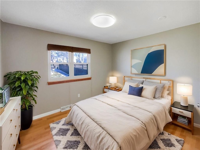 bedroom with visible vents, light wood-style flooring, and baseboards