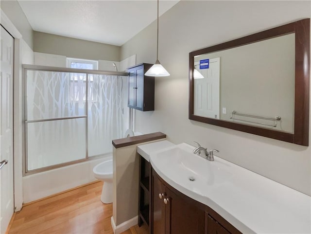 full bathroom with wood finished floors, vanity, toilet, and bath / shower combo with glass door