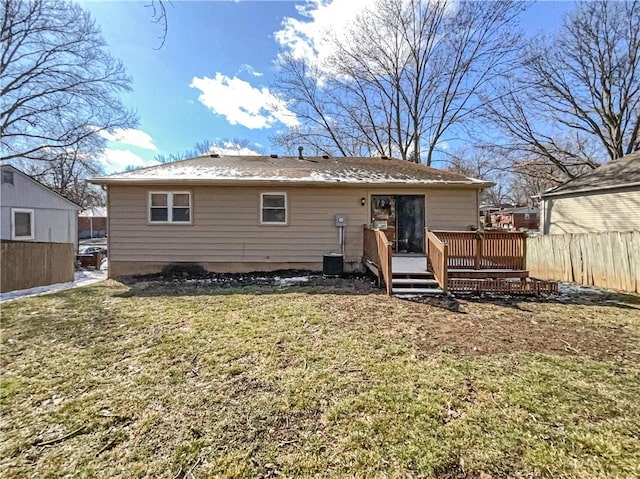 rear view of property featuring a yard, a wooden deck, and fence