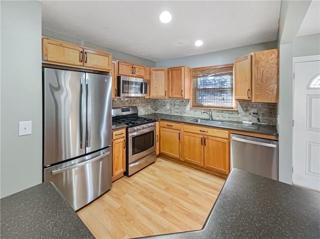 kitchen featuring decorative backsplash, appliances with stainless steel finishes, light wood-type flooring, a sink, and recessed lighting