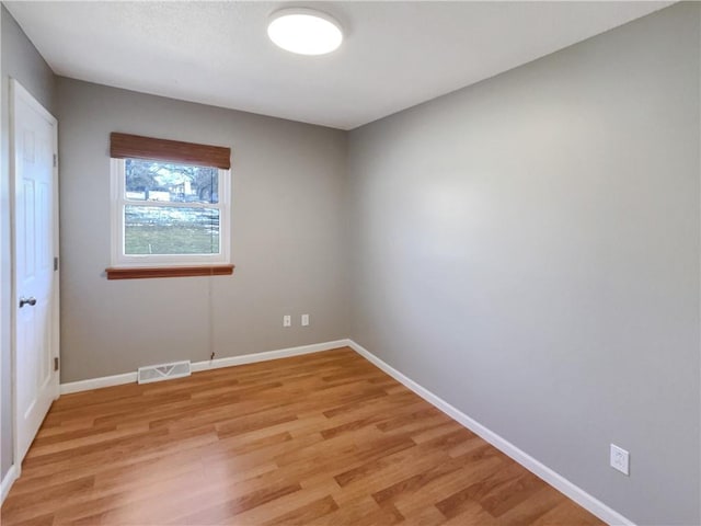 spare room featuring light wood-style flooring, visible vents, and baseboards