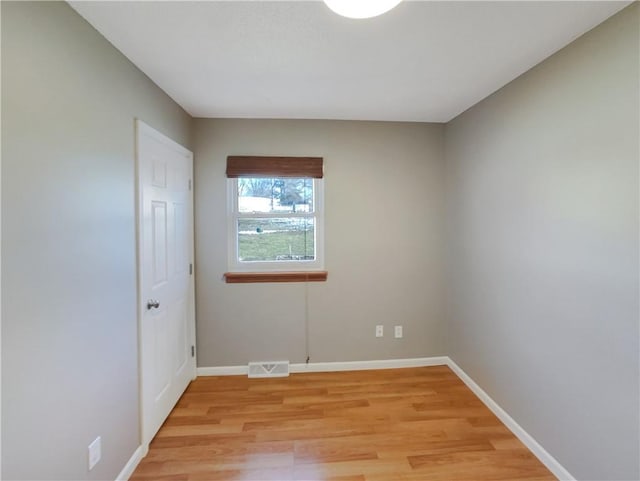 empty room featuring light wood-style floors, visible vents, and baseboards