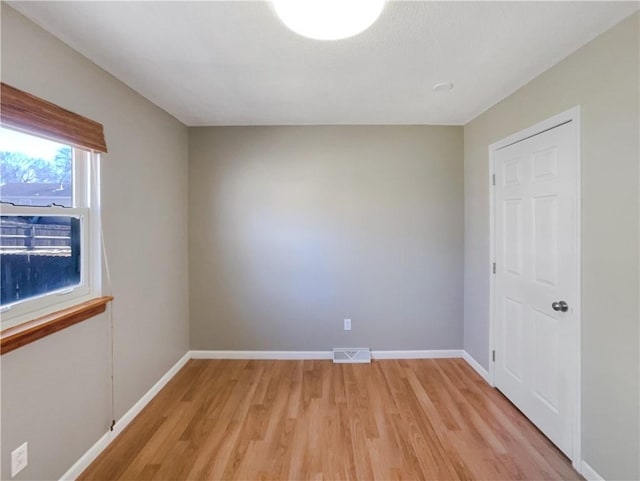 unfurnished room featuring light wood-style flooring, visible vents, and baseboards