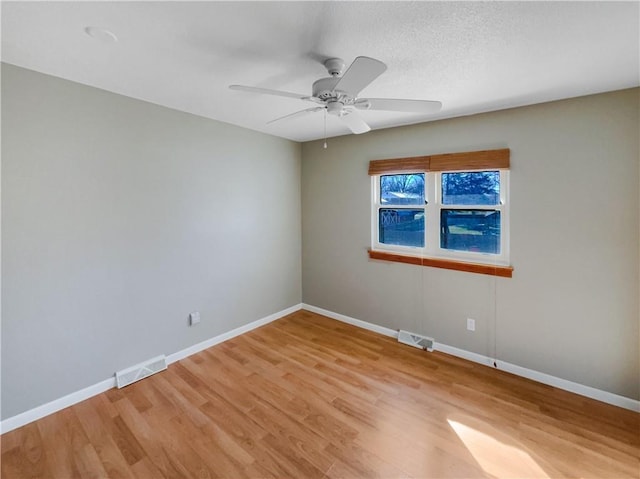 empty room with light wood-style floors, visible vents, and baseboards