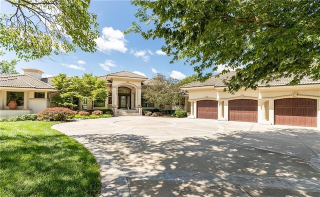 mediterranean / spanish house with concrete driveway, a front yard, a tile roof, and stucco siding