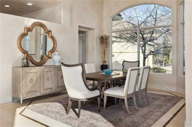 dining space with recessed lighting, a high ceiling, plenty of natural light, and baseboards