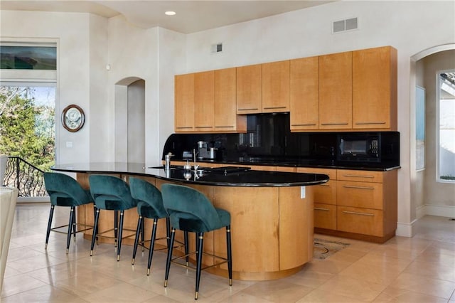 kitchen featuring dark countertops, visible vents, black microwave, and decorative backsplash